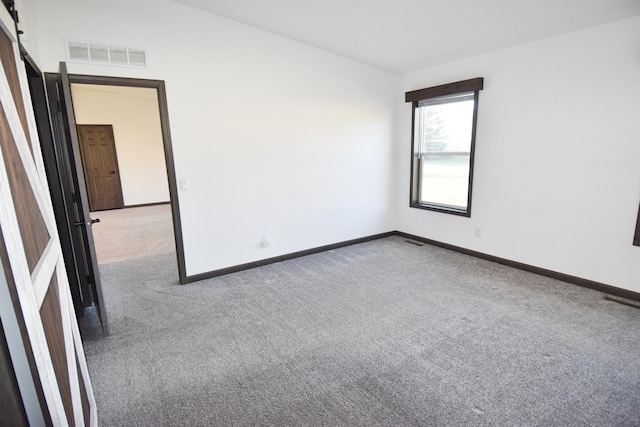 unfurnished room with carpet floors and a barn door