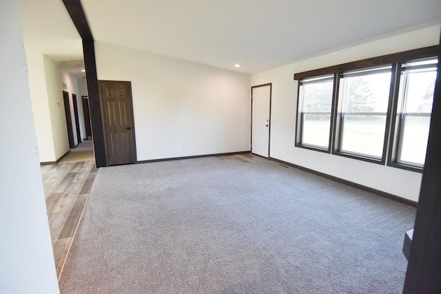 carpeted spare room with lofted ceiling