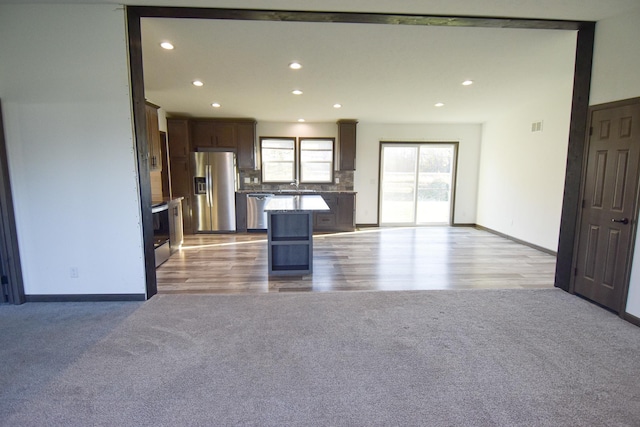 kitchen featuring sink, appliances with stainless steel finishes, a kitchen breakfast bar, light hardwood / wood-style flooring, and a center island