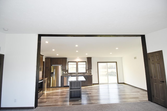 kitchen with appliances with stainless steel finishes, light hardwood / wood-style floors, a breakfast bar area, and a kitchen island