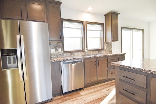 kitchen featuring stainless steel appliances, light hardwood / wood-style floors, backsplash, and plenty of natural light