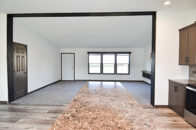 unfurnished living room featuring light colored carpet and vaulted ceiling