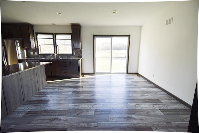 kitchen featuring hardwood / wood-style floors, a wealth of natural light, backsplash, and stainless steel refrigerator