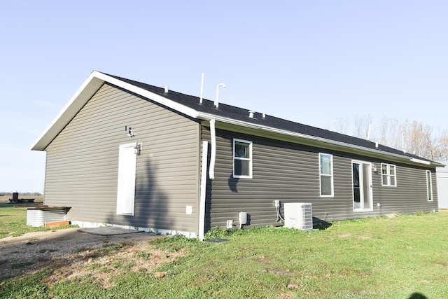 rear view of property featuring central AC unit and a yard