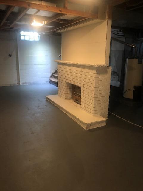 basement featuring a brick fireplace and water heater