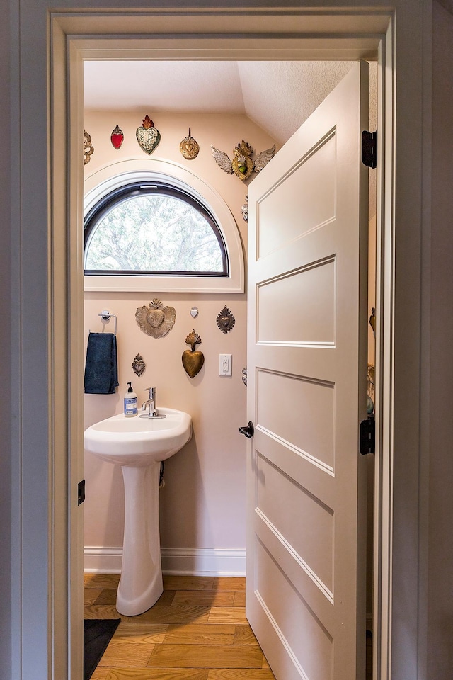 bathroom with a textured ceiling, lofted ceiling, and hardwood / wood-style floors