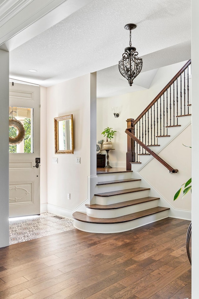 foyer entrance with a notable chandelier, a textured ceiling, and dark hardwood / wood-style flooring