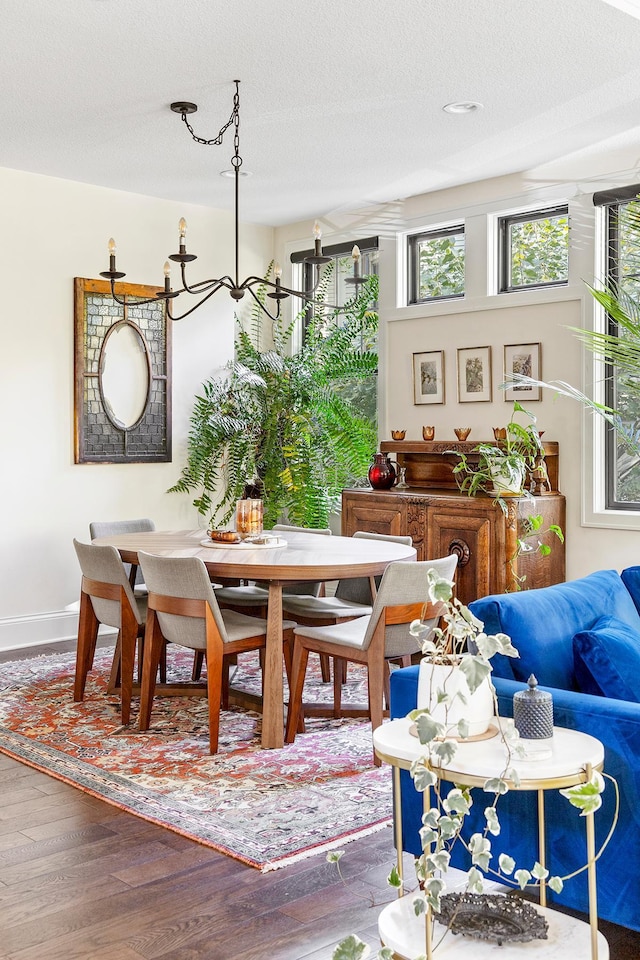 dining room with wood-type flooring, a textured ceiling, and an inviting chandelier