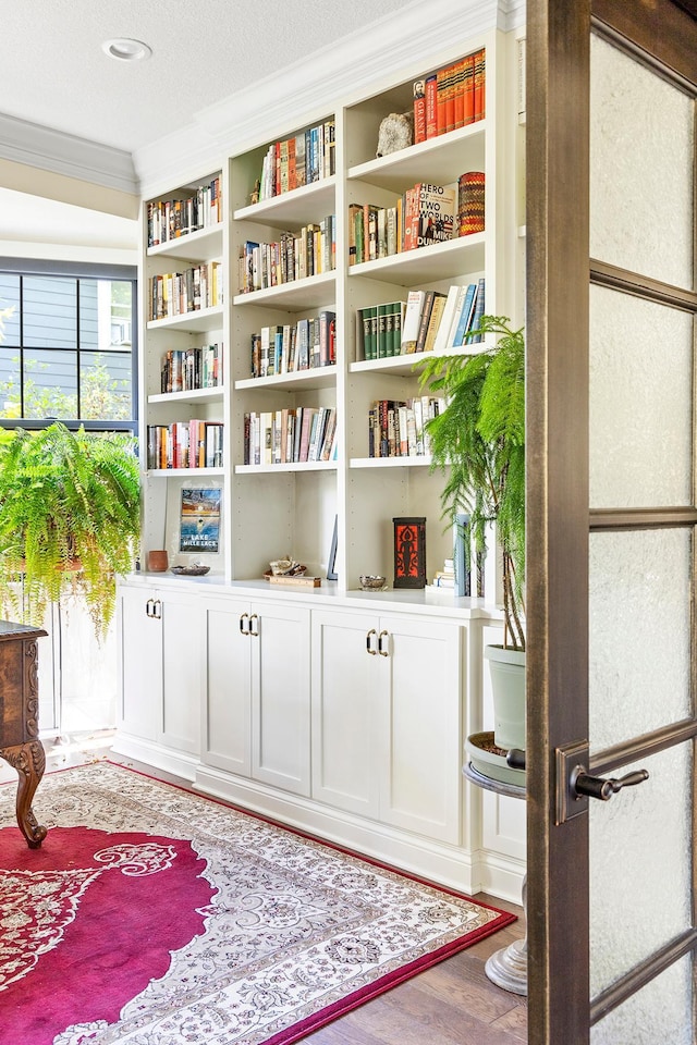 sitting room with hardwood / wood-style flooring, ornamental molding, a textured ceiling, and built in features