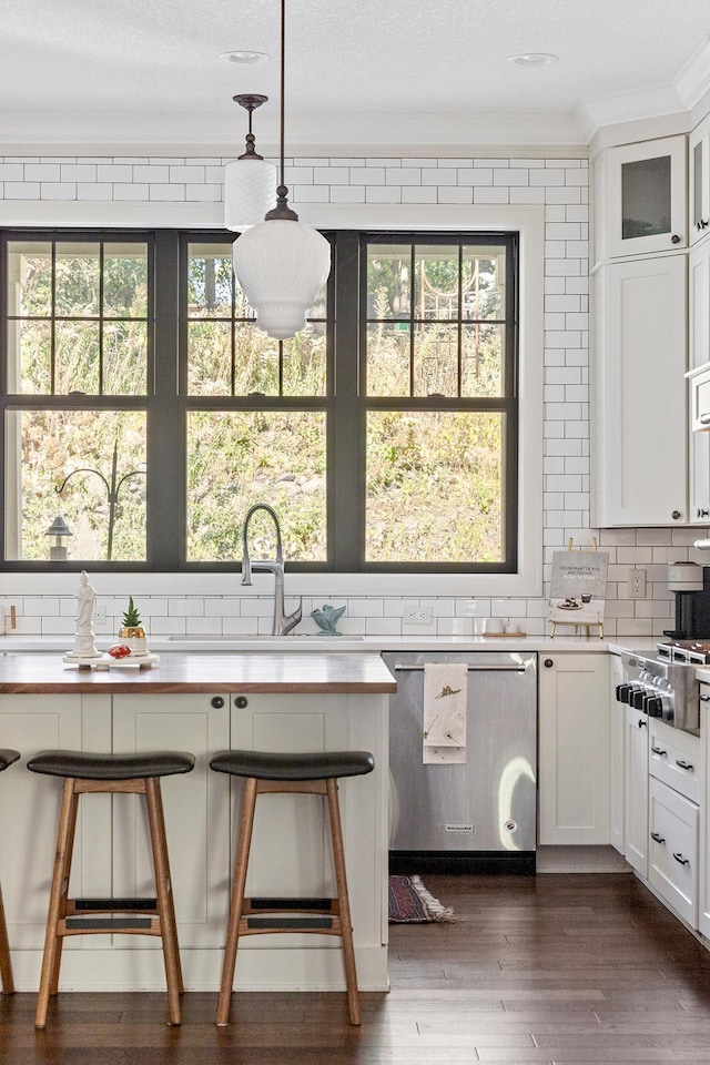 kitchen featuring ornamental molding, white cabinets, hanging light fixtures, and a wealth of natural light