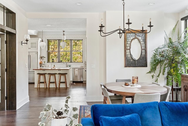 dining area with an inviting chandelier, a textured ceiling, sink, and dark hardwood / wood-style flooring