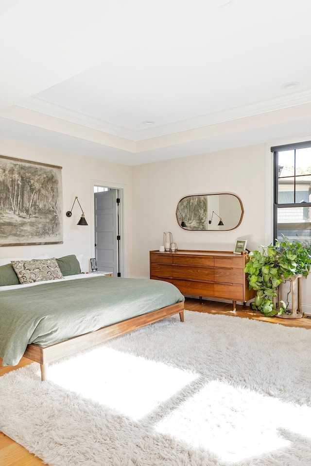 bedroom with crown molding, a tray ceiling, and hardwood / wood-style floors