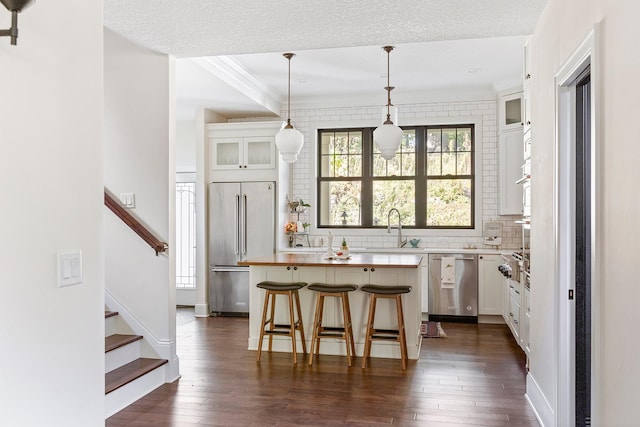 kitchen with appliances with stainless steel finishes, a kitchen bar, a kitchen island, dark hardwood / wood-style flooring, and white cabinets