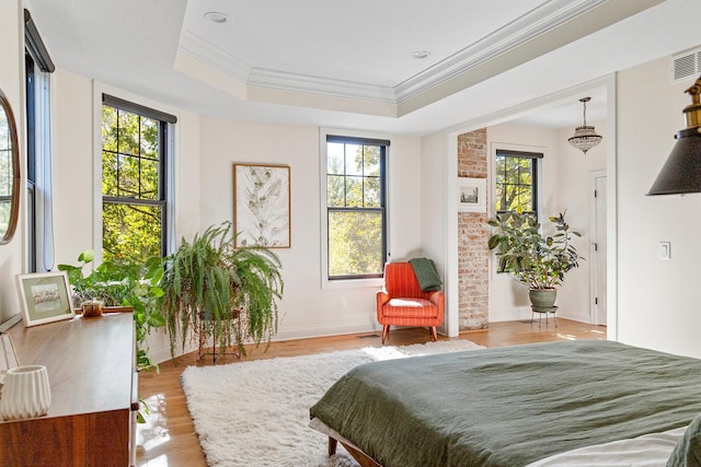 bedroom with crown molding, light hardwood / wood-style flooring, multiple windows, and a tray ceiling