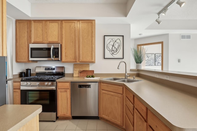 kitchen with rail lighting, sink, stainless steel appliances, light tile patterned floors, and a textured ceiling