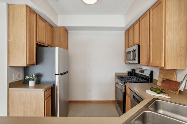 kitchen with stainless steel appliances, sink, light tile patterned floors, and a textured ceiling