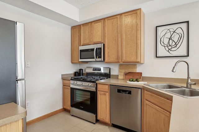 kitchen featuring light brown cabinetry, light tile patterned floors, stainless steel appliances, and sink