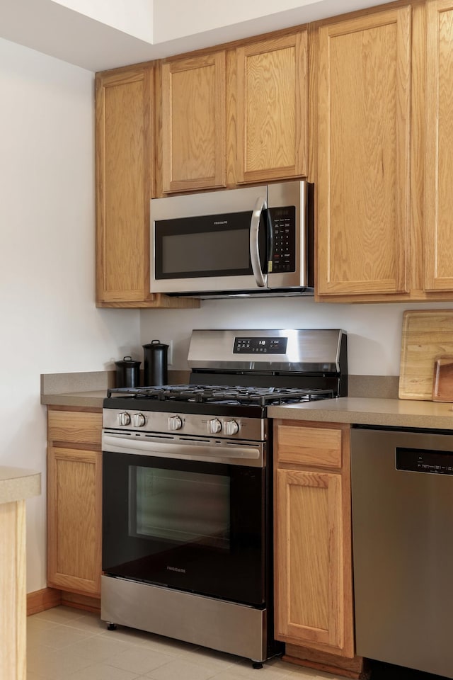 kitchen with light brown cabinets, appliances with stainless steel finishes, and light tile patterned floors