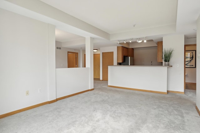 unfurnished living room featuring track lighting and light colored carpet