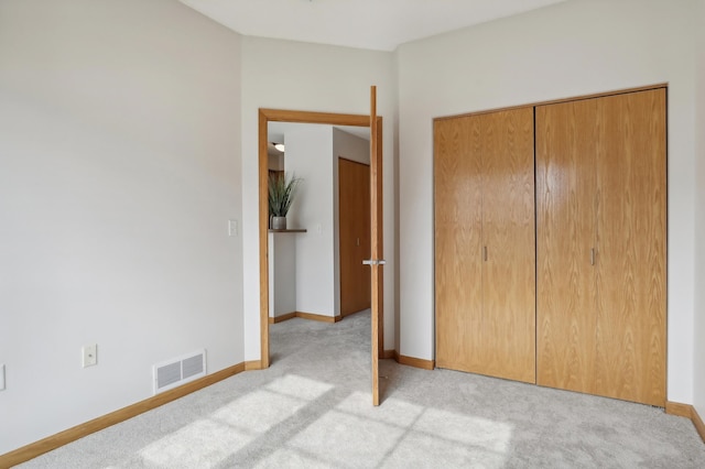 unfurnished bedroom featuring light colored carpet and a closet