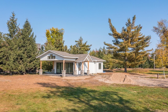 rear view of house featuring a yard and covered porch