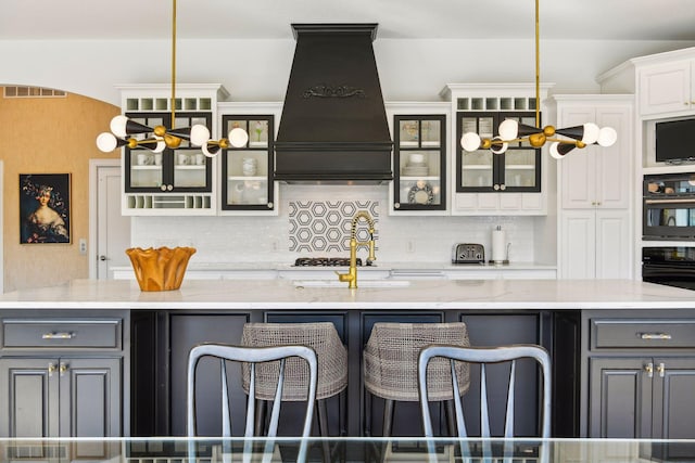 kitchen featuring gray cabinetry, decorative light fixtures, white cabinets, decorative backsplash, and premium range hood