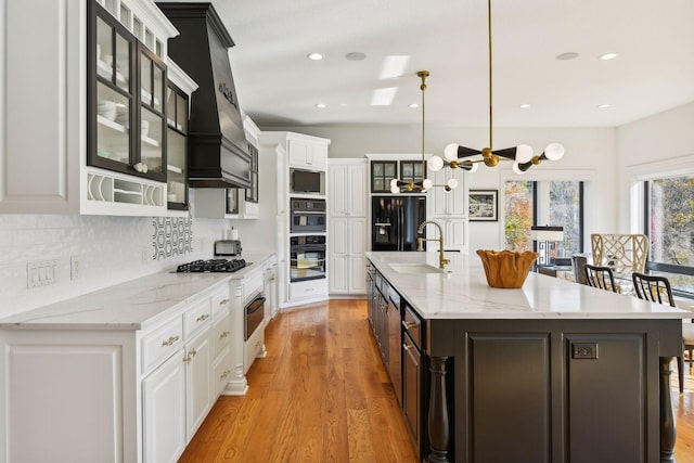 kitchen featuring white cabinetry, a large island, sink, and hanging light fixtures