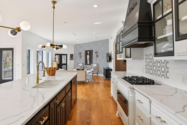 kitchen featuring hanging light fixtures, dark brown cabinets, sink, white cabinets, and light stone counters