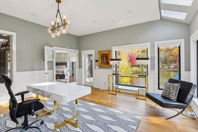 office featuring vaulted ceiling with skylight, a notable chandelier, and light wood-type flooring