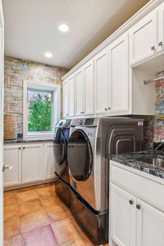 clothes washing area featuring washer and dryer and cabinets