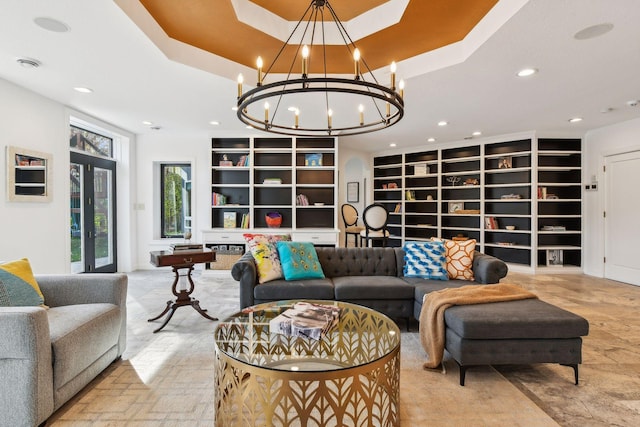 living room featuring an inviting chandelier, french doors, built in features, and a raised ceiling