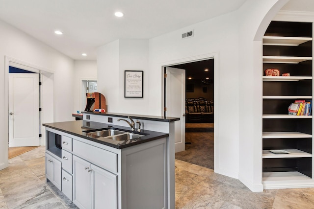 kitchen with gray cabinets, sink, and an island with sink