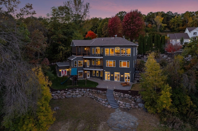 back house at dusk featuring a balcony