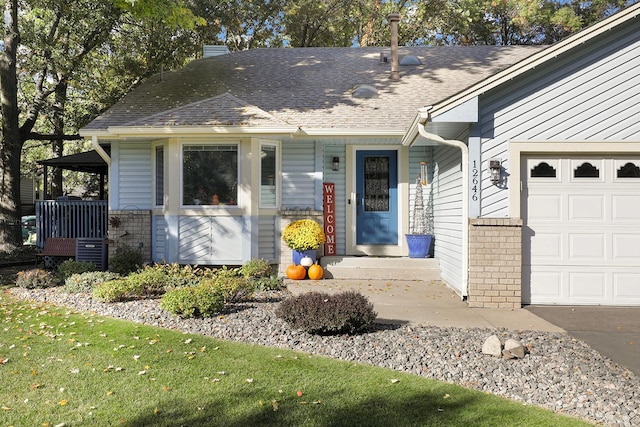 view of front of property featuring a garage, brick siding, a chimney, and a shingled roof