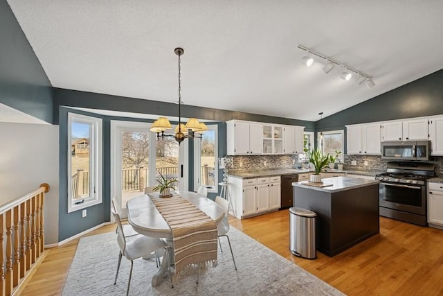 kitchen featuring vaulted ceiling, stainless steel appliances, white cabinets, and a center island