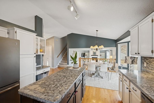 kitchen with light wood-style flooring, white cabinetry, vaulted ceiling, freestanding refrigerator, and decorative backsplash