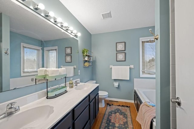 full bath with visible vents, a sink, toilet, and wood finished floors