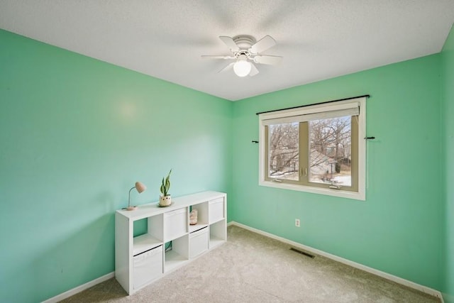 interior space with baseboards, visible vents, light colored carpet, ceiling fan, and a textured ceiling