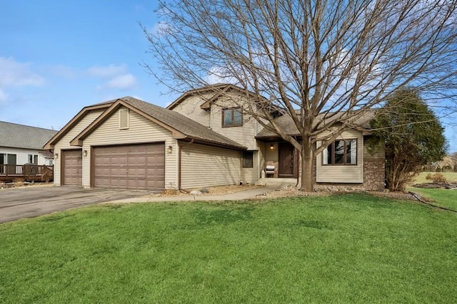 split level home with a garage, driveway, a front lawn, and brick siding