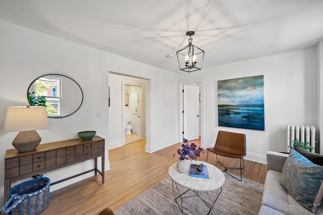 living room featuring radiator, light hardwood / wood-style floors, and a chandelier