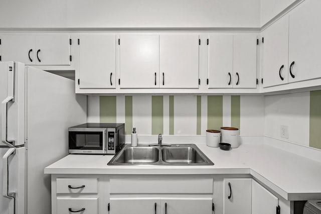 kitchen featuring white fridge, sink, and white cabinets