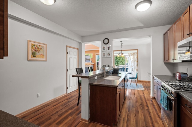 kitchen with a center island with sink, dark hardwood / wood-style flooring, sink, appliances with stainless steel finishes, and a kitchen breakfast bar