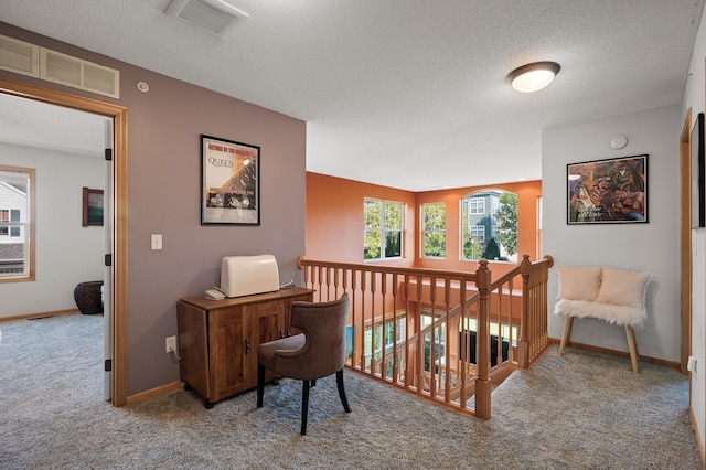 carpeted office space featuring visible vents, a textured ceiling, and baseboards