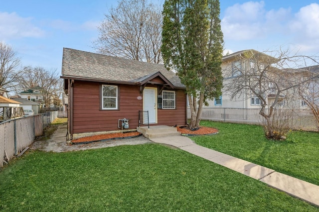 bungalow-style home with roof with shingles, fence, and a front lawn