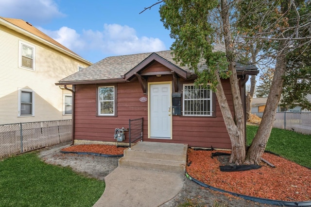 bungalow-style house with fence and a shingled roof