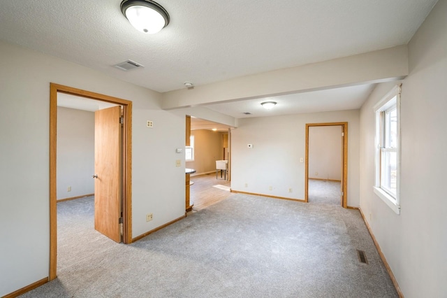 carpeted empty room with a textured ceiling, baseboards, and visible vents