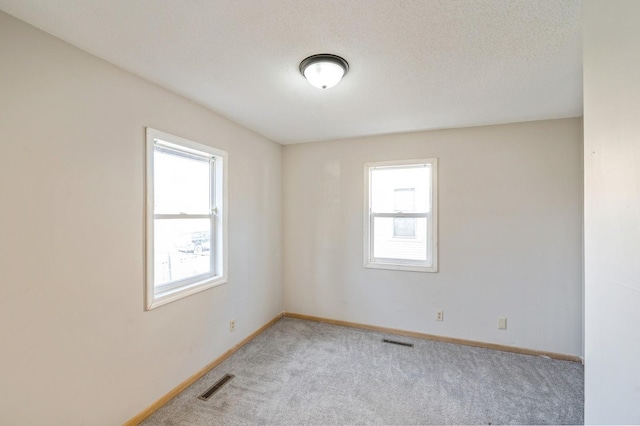 carpeted spare room with a textured ceiling