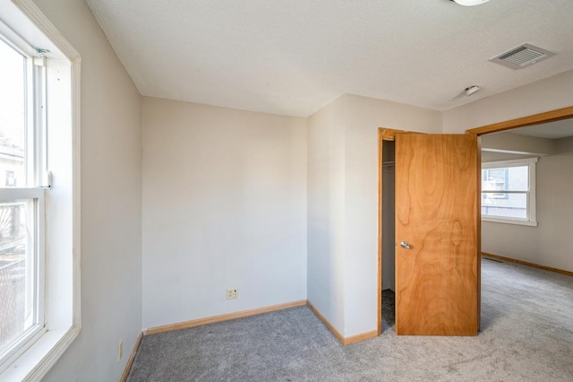 unfurnished room with light carpet and a textured ceiling