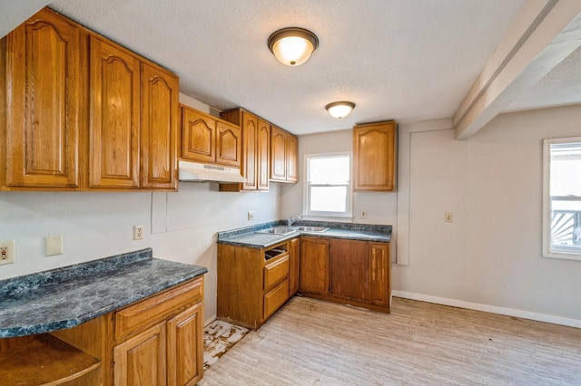 kitchen featuring plenty of natural light, dark stone counters, light hardwood / wood-style flooring, and a textured ceiling