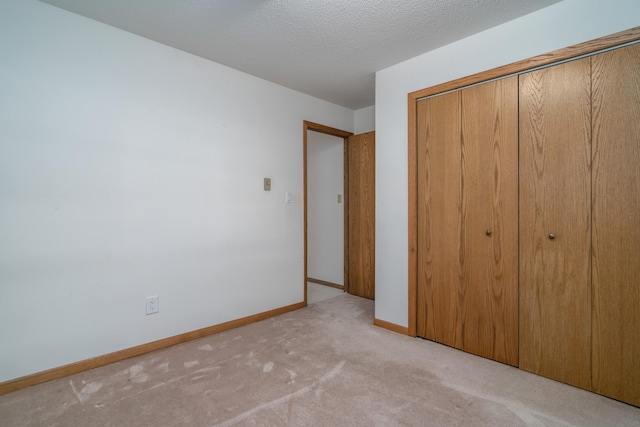 unfurnished bedroom with a textured ceiling, light colored carpet, and a closet